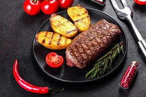 ribeye steak met aardappelen, uien en cherrytomaatjes foto