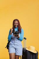 vrolijk volwassen controle afbeeldingen Aan DSLR, op zoek Bij foto's van architectuur gebouwen en landschappen in studio met koffer. vrouw bezienswaardigheden bekijken en nemen foto's Aan vakantie. foto