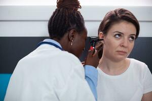 otologie specialist dokter controle voor geduldig oorpijn, gescheurd trommelvlies, tinnitus en doofheid oor symptomen. medisch gebruik makend van otolaryngologie instrument in kliniek kantoor gedurende medisch afspraak foto