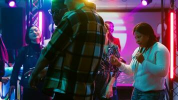 multi-etnisch groep van mensen dansen, gevoel funky Aan muziek- Bij de club. vrienden genieten van leven prestatie Aan dans vloer, tonen dans beweegt onder disco lichten en feesten. statief schot. foto