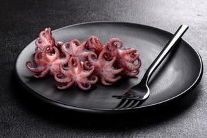 zeevruchten baby octopus salade in een zwarte plaat foto