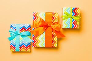 geschenk doos met blauw, groen en oranje boog voor Kerstmis of nieuw jaar dag Aan oranje achtergrond, top visie foto