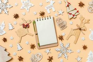 feestelijk decoraties en speelgoed Aan oranje achtergrond. top visie van notebook. vrolijk Kerstmis concept foto