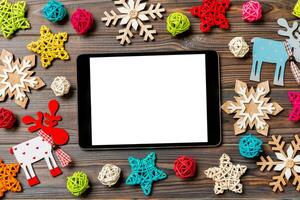 top visie van tablet Aan vakantie houten achtergrond. nieuw jaar decoraties en speelgoed. Kerstmis concept foto