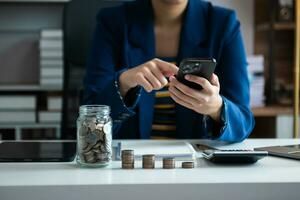 geld besparen met de hand munten in het glas van de kan en rekenmachine te plaatsen om de financiën en boekhouding van het budgetconcept te berekenen foto