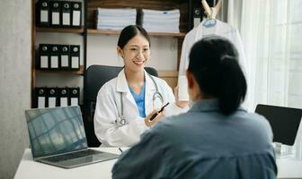 Azië vrouw dokter gebruik makend van klembord is leveren Super goed nieuws praten bespreken resultaten of symptomen met vrouw geduldig in kliniek of ziekenhuis foto