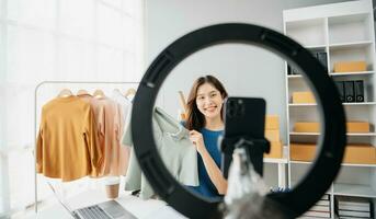 Aziatisch dame blogger tonen kleren in voorkant van de camera naar opname vlog video leven streaming foto