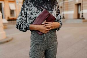 mode voorwerpen. zwart vrouw Holding in handen luxe zak . sieraden armband Aan hand. grijs fluweel trui. foto
