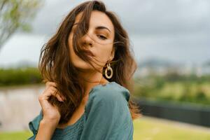 dichtbij omhoog portret van elegant brunette vrouw in modieus Bijsnijden blouse met bladerdeeg mouw poseren in luxe hotel Aan de dak top. foto