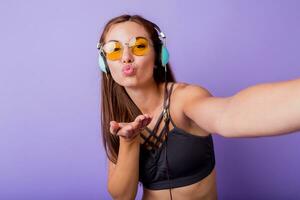 zorgeloos brunette meisje maken zelf portret , luisteren muziek- en genieten van opleiding . perfect bruinen sportief lichaam. foto