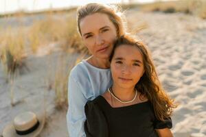 buitenshuis portret van mooi familie. moeder en dochter poseren Aan de strand. warm zonsondergang kleuren. foto