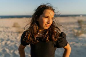 mooi brunette kind meisje poseren om de strand. zonsondergang warm kleuren. foto