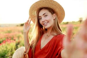 vers lief blond vrouw maken zelf portret terwijl wandelen langs de papaver veld- in warm zomer avond foto