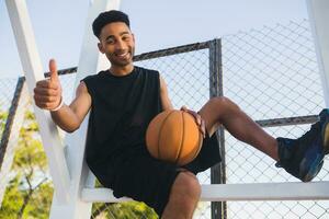 zwart Mens aan het doen sport, spelen basketbal Aan zonsopkomst, actief levensstijl, zonnig zomer ochtend- foto