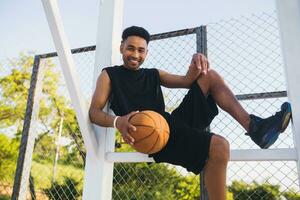 zwart Mens aan het doen sport, spelen basketbal Aan zonsopkomst, actief levensstijl, zonnig zomer ochtend- foto