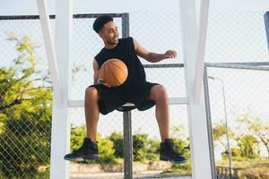 zwart Mens aan het doen sport, spelen basketbal Aan zonsopkomst, actief levensstijl, zonnig zomer ochtend- foto