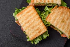 heerlijk krokant belegd broodje met geroosterd brood, Zalm, avocado, tomaten, zout, specerijen en kruiden foto