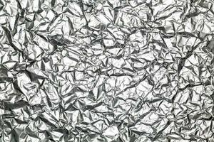 zilver blad folie achtergrond met glimmend verfrommeld ongelijk oppervlakte voor structuur en achtergrond foto