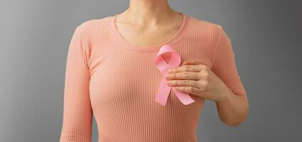 borst kanker bewustzijn campagne concept. Dames gezondheidszorg. dichtbij omhoog van een jong vrouw aanraken roze lint Aan haar thorax foto