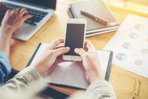 de handen van de zakenvrouw die aan slimme telefoon en bedrijfsinformatie werken foto