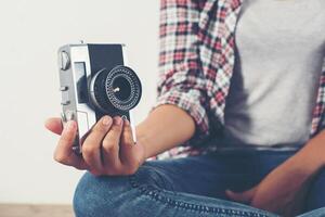 jonge hipster fotograaf vrouw die foto neemt en naar de camera kijkt