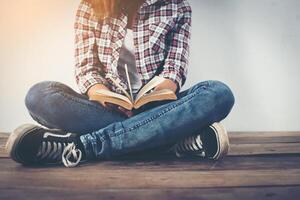 jonge hipster vrouw met open boek zittend op houten vloer. foto