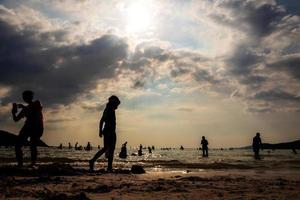 silhouetten van mensen die in de zee spelen op een openbaar strand foto