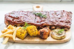 gegrilde varkensribbetjes met barbecuesaus en groente en franse frietjes foto