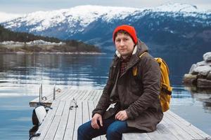 reiziger man zit op houten pier op de achtergrond van mountain foto