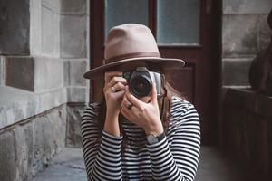 mooie vrouw met hoed maakt foto met ouderwetse camera