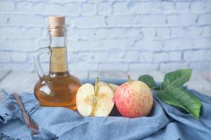 appelazijn in glazen fles met verse groene appel op tafel foto