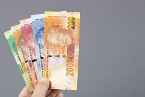 zuiden Afrikaanse geld in de hand- Aan een grijs achtergrond foto