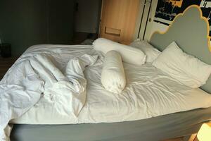 rommelig hotel bed. wit kussen. wit rollen. wit deken. foto