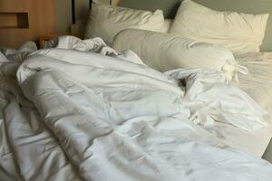 rommelig hotel bed. wit kussen. wit rollen. wit deken. foto