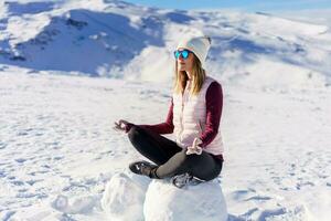 vrolijk vrouw mediteren in lotus houding Aan sneeuw foto