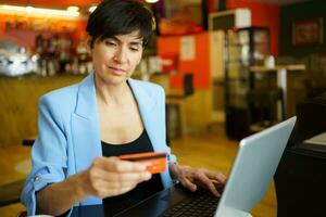 gefocust vrouw gebruik makend van credit kaart en laptop in cafe foto