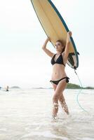 surfer meisje met haar surfboard Aan de strand. foto