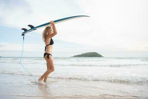 surfer meisje met haar surfboard Aan de strand. foto