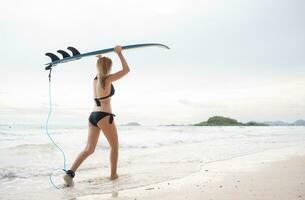 surfer meisje met haar surfboard Aan de strand. foto