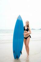 surfer meisje met haar surfboard Aan de strand. foto