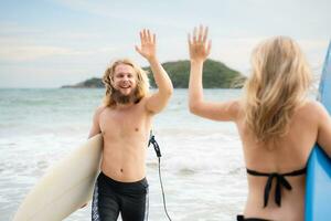 twee surfers geven hoog vijf Aan de strand. twee surfers hebben pret Aan de strand. foto