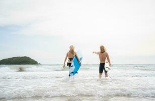 jong Mens en vrouw Holding surfplanken klaar naar wandelen in de zee naar surfen. foto