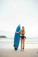 surfer meisje met haar surfboard Aan de strand. foto