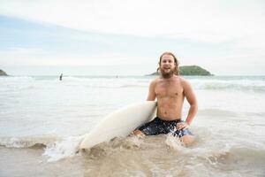 jong Mens surfing Aan de strand hebben pret en balanceren Aan de surfboard foto