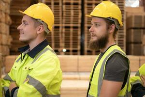 groep van arbeiders in een groot hout fabriek, hebben pret door verhogen uw armen na voltooien de dag werk. foto