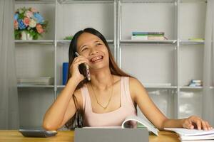 vrouw werken Bij huis gebruik uw telefoon en computer naar communiceren met uw teamgenoten. foto
