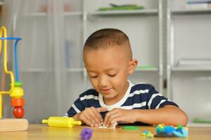 jongen maken plasticine naar promoten ontwikkeling Aan de tafel in de huis. foto