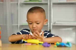 een jongen kneedt plasticine naar maken dingen zacht. foto