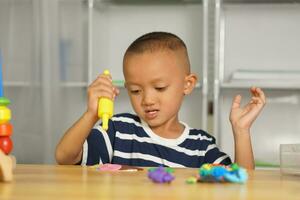 jongen maken plasticine naar promoten ontwikkeling Aan de tafel in de huis. foto