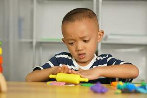 een jongen kneedt plasticine naar maken dingen zacht. foto